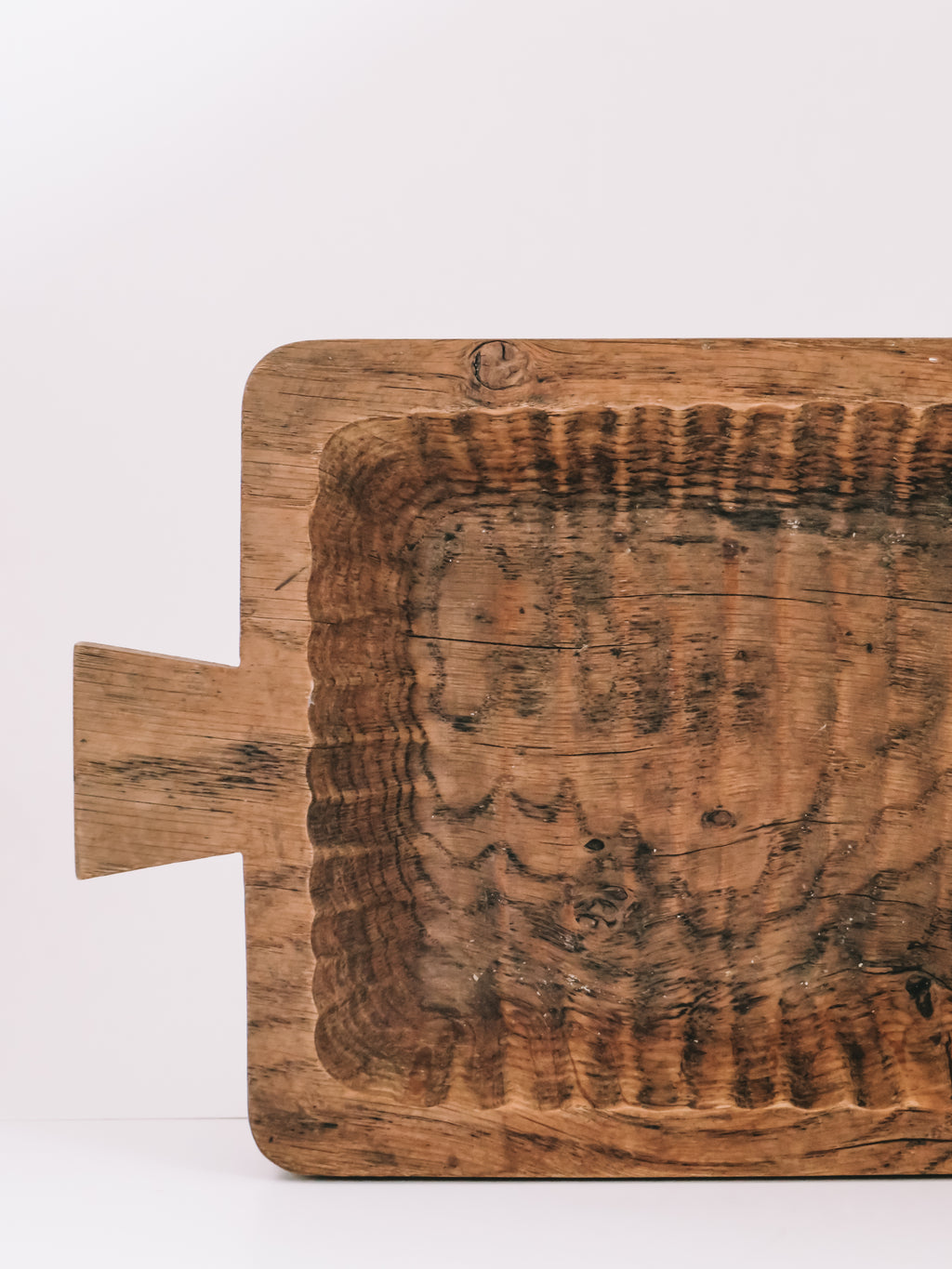 A rustic rectangular wooden serving board with a handle, featuring a heavily charred or burnt center section and dark grain patterns, photographed against a plain white background.