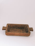 A rustic rectangular wooden bowl with side handles, shown on a plain light gray background.