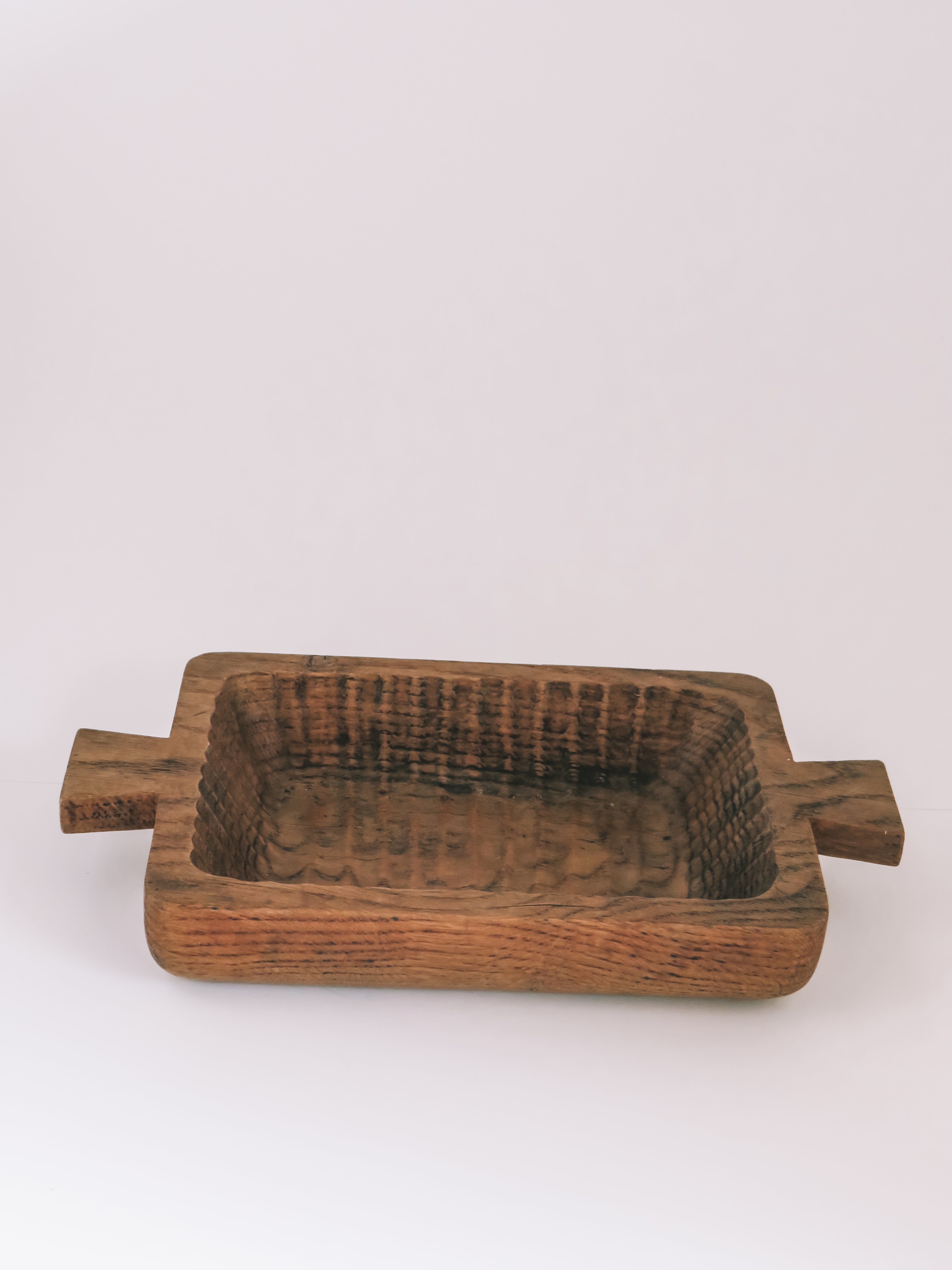 A rustic rectangular wooden bowl with side handles, shown on a plain light gray background.