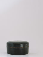 A small round black lacquered box with a lid, photographed on a clean white studio background.