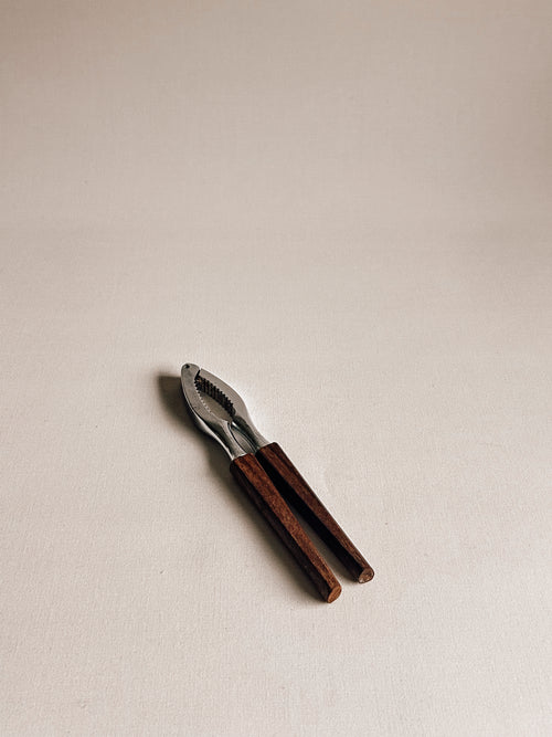 A small hand tool with dark brown wooden handles and a silver metal head, photographed on a plain light beige background.